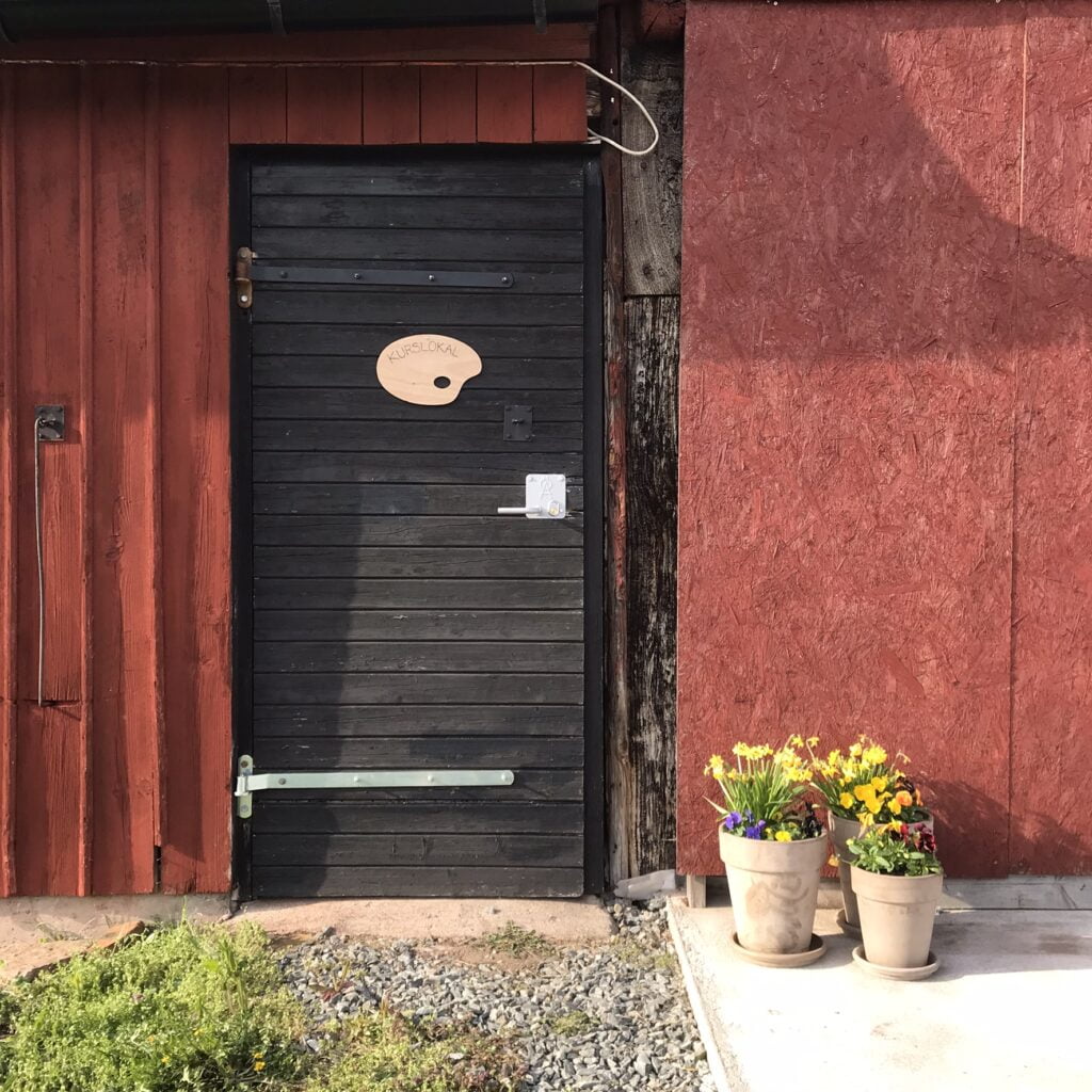 Svart dörr med blommor vid sidan